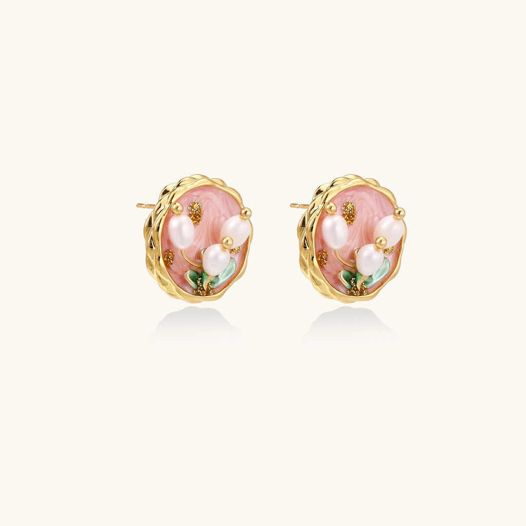 Round stud earrings with pink enamel background, white pearl tulips, green leaves, and twisted gold border on white background.