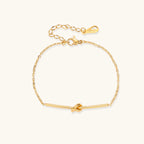 Delicate gold-plated chain bracelet with twisted knot bar detail and adjustable extender chain on white background.