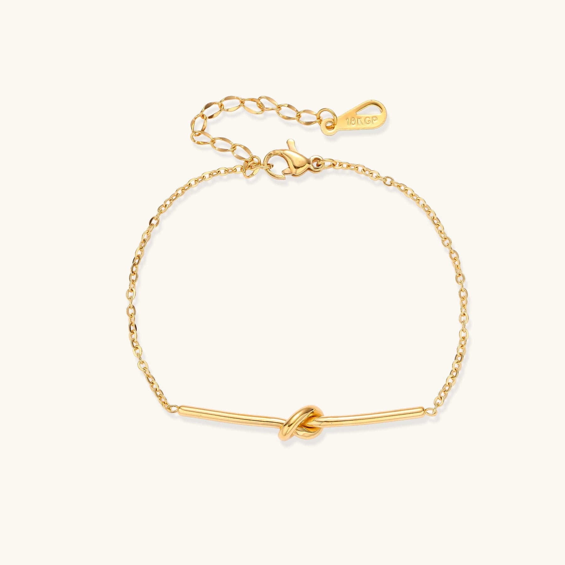 Delicate gold-plated chain bracelet with twisted knot bar detail and adjustable extender chain on white background.
