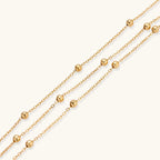 Delicate 18K gold plated bracelet with spherical beads on layered chains and adjustable extender on white background