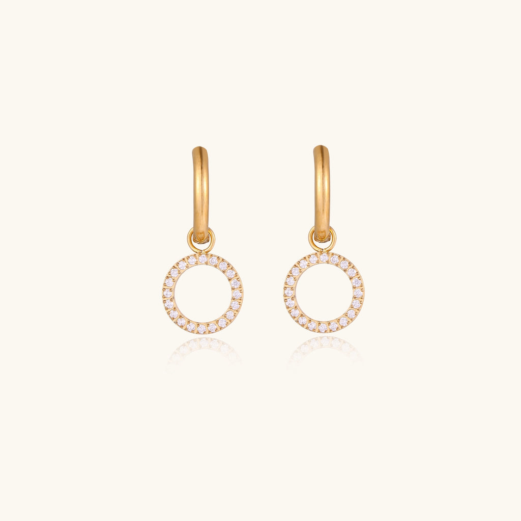 Gold-plated hoop earrings with circular cubic zirconia charm dangles displayed on neutral background.