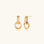 Geometric gold earrings with ribbed linear top section and circular drop elements on white background.