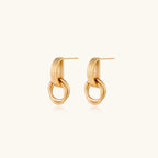 Geometric gold earrings with ribbed linear top section and circular drop elements on white background.